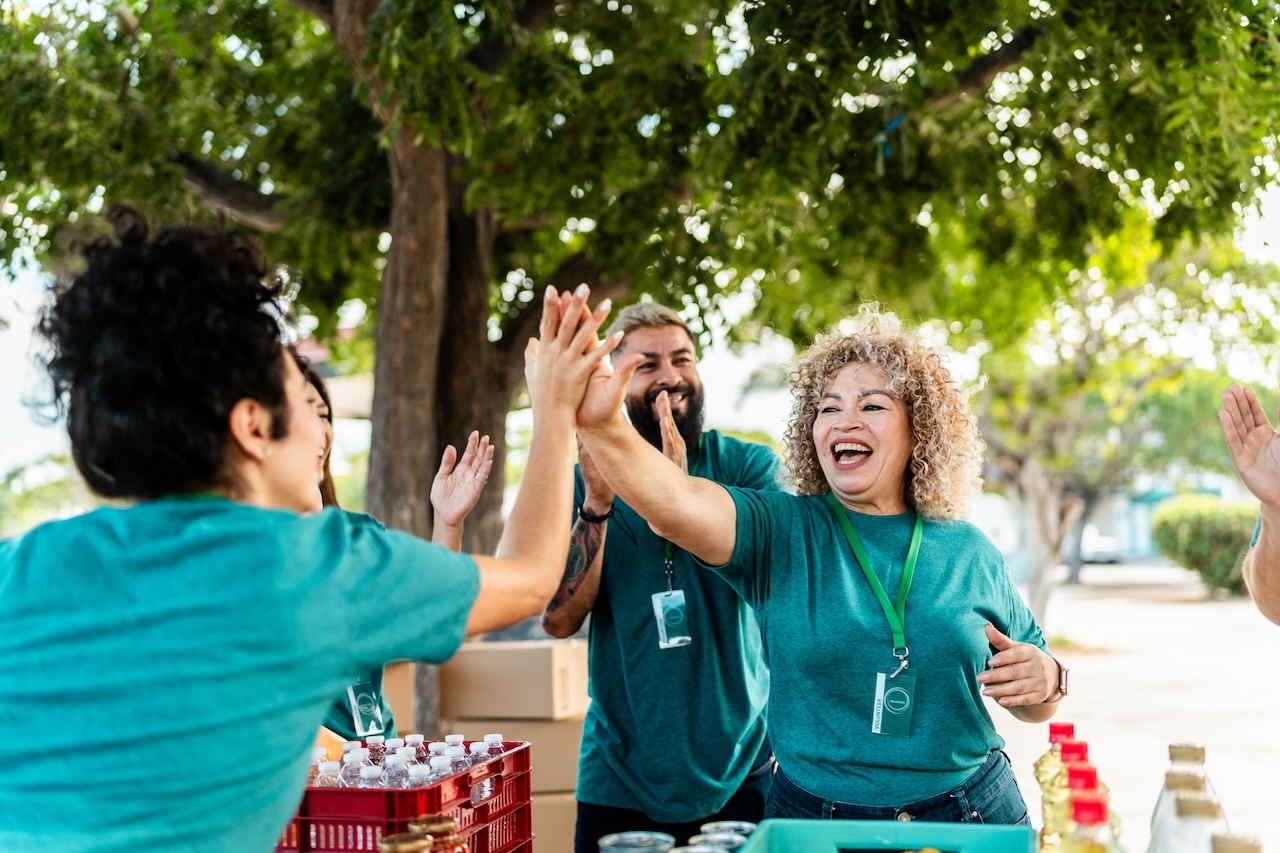 Volunteer organizing donation boxes and doing high-five outdoors
